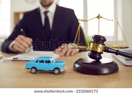 Miniature car near with judge gavel symbolize litigation and legal problems associated with purchase and ownership of personal vehicles or leasing placed on table in front of lawyer. Selective focus Royalty-Free Stock Photo #2332060173