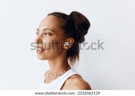 Woman with tanned skin portrait listening to music on wireless headphones and smiling with her teeth on a white background. Technology and lifestyle