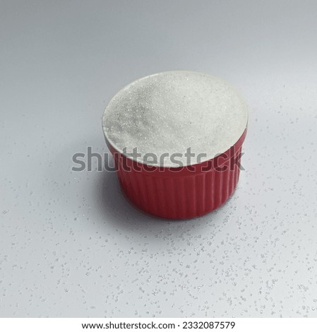 Sugar in a red cup lies on a white background