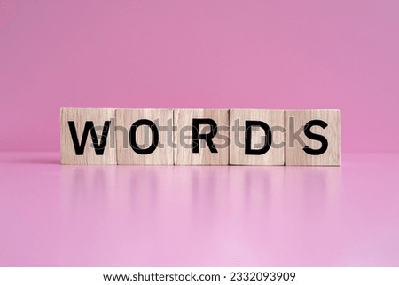 Wooden blocks form the text "WORDS" against a pink background.