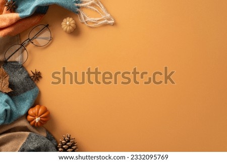Above view of a warm and cozy autumn ambiance at home. Glasses, patchy scarf, pumpkin candles, maple foliage and aromatic chinese anise create a perfect brown backdrop for text or advert placement