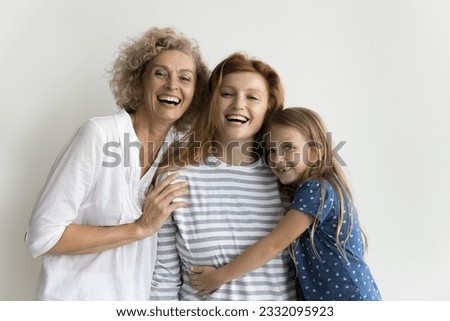 Happy pretty grandma, mother and little kid girl hugging at white background with love, affection, looking at camera, smiling, laughing, having fun, posing for family portrait