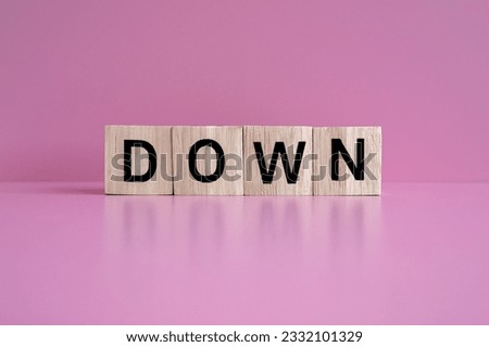 Wooden blocks form the text "DOWN" against a pink background.