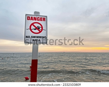 No Swimming area sign post plaque on sea water background. No swim area signage pillar, mounted on the shore sea beach. Outdoors