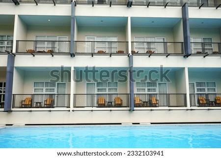 
Multi-storey hotel building with many rooms, doors and windows facing the swimming pool.