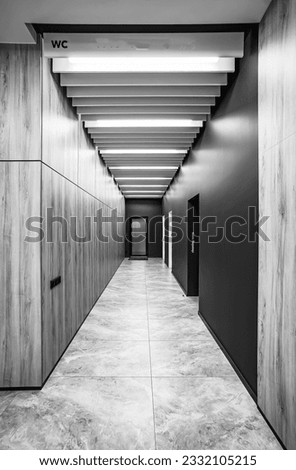 Perspective of a long corridor in office building. Doors of washrooms in hallway. Doors office with wc signs. Entrance to restrooms in a factory