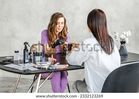 Professional master manicurist at beauty salon. Manicure service, hands treatments, procedures for nails, fingers. Multi-colored nail polish, samples palette, tattoos, cuticle oil, gel uv lamp,gloves. Royalty-Free Stock Photo #2332123269