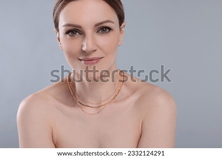 Beautiful woman with elegant necklace on light grey background