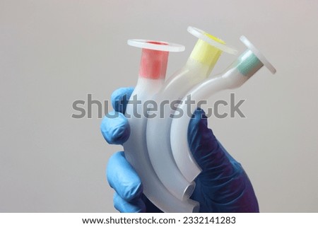 Different sizes of an oropharyngeal airway cannula in a healthcare professional wearing gloves.  Royalty-Free Stock Photo #2332141283