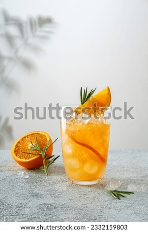 Tequila sunrise cocktail in glass with ice, refreshing summer drink. Cold and refreshing orange punch cocktail with orange slice.  Sunny day shadows.  A refreshing summer cocktail Royalty-Free Stock Photo #2332159803