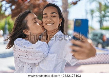 Two women mother and daughter make selfie by smartphone at park