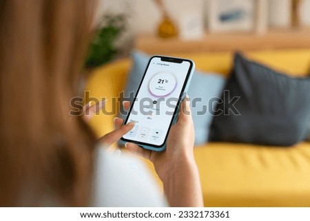 Woman controlling the temperature with a mobile phone.