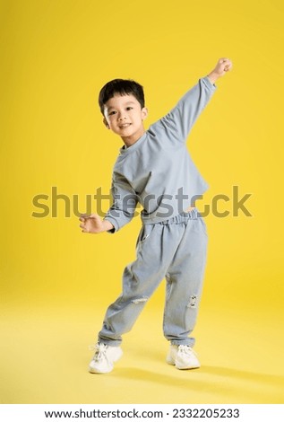 full body image of boy posing on a yellow background
