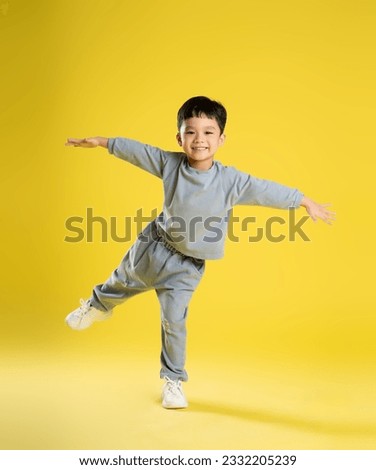 full body image of boy posing on a yellow background
