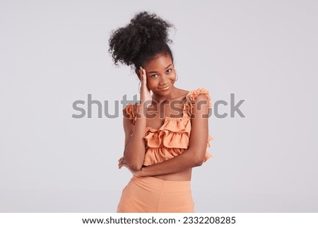 With confidence and grace, a black girl in an orange shirt shines in a fashion shoot, showcasing her impeccable style and captivating beauty.