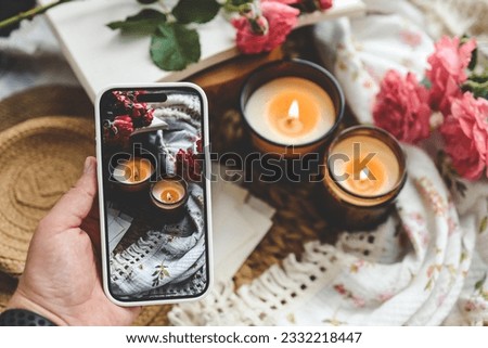 Girl makes a photo, two burning candles in a spring interior.