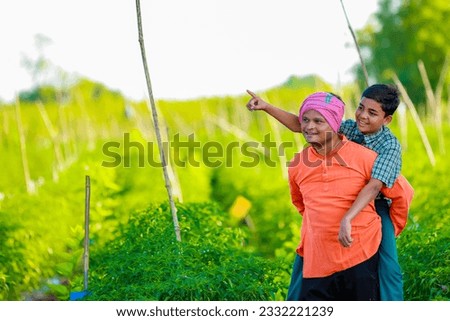 Indian farmer with his son at agriculture field,  Father and son are standing in farm, They are happy because of successful sowing and enjoying sunset
