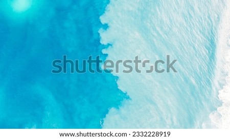 Top view of light blue water with white sand. Waves raise sand and a mix with turquoise water is obtained. Shadows from clouds on a clear ocean. Clear sea. Gradient of blue. The background photo Royalty-Free Stock Photo #2332228919
