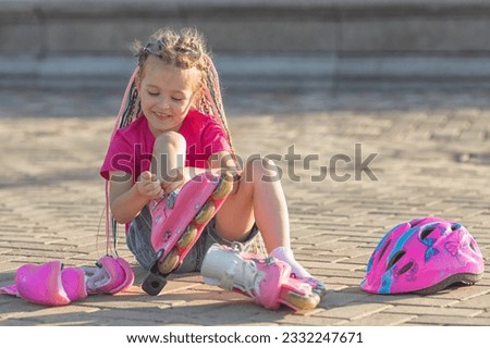 Little girl preschool sitting wearing her roller skates and crossing her legs. children's hobby. sports lifestyle