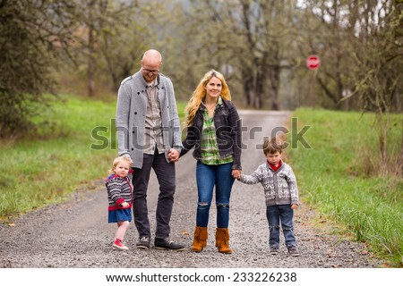 Family photo of a mother, father, and their two kids a boy and girl outdoors in the Fall.
