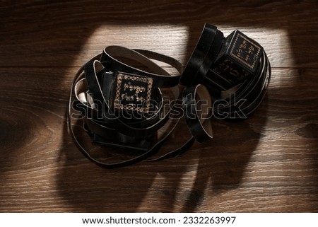 A photograph of ritual Jewish prayer vestments with a hebrew inscription reading: On one object the symbols read: "Tefillin for the hand", on the second they read: "Tefillin for the head" Royalty-Free Stock Photo #2332263997