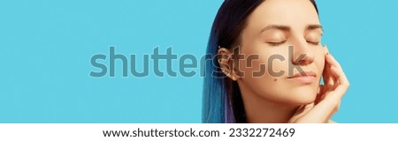 Face of young beautiful woman with blue hair on bright background