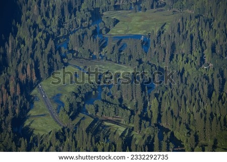 Beautiful aerial view of the very lush green meadows and pine forests in Yosemite Valley with a winding high water Merced river in Yosemite National Park, California 