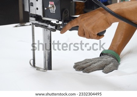Straight knife cutter and stainless steel gloves in a clothing factory Royalty-Free Stock Photo #2332304495