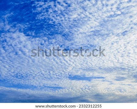 Altocumulus floccus with Sunbeams Clouds, Sunlight, white fluffy clouds covering the blue sky. A mackerel sky for clouds of Altocumulus rippling pattern similar in appearance to fish scales. Royalty-Free Stock Photo #2332312255