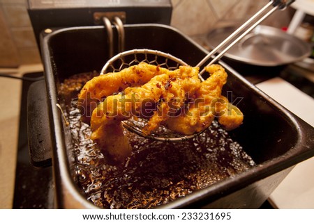 Chicken tenders fried in a deep fryer. Royalty-Free Stock Photo #233231695