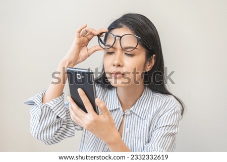 Presbyopia, Hyperopia middle aged asian woman holding eyeglasses problem with vision blurred ,trying to read text message from smart mobile phone screen, eye disease of old, eyesight farsightedness. Royalty-Free Stock Photo #2332332619