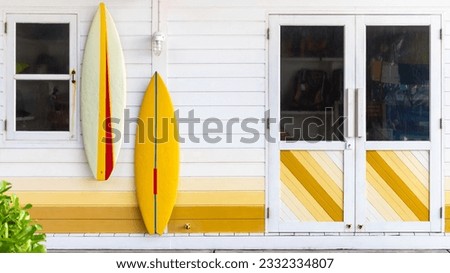 Colorful facade wall with surfboards hanging on it with door and window background. Royalty-Free Stock Photo #2332334807