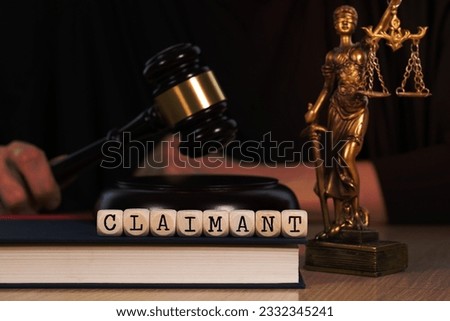 Word  CLAIMANT composed of wooden dices.  Wooden gavel and statue of Themis in the background. Closeup Royalty-Free Stock Photo #2332345241