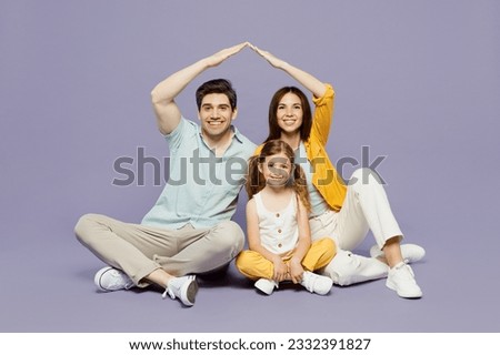 Full body young happy parents mom dad with child kid daughter girl 6 years old wear blue yellow casual clothes sit hold hands above head pov roof isolated on plain purple background Family day concept Royalty-Free Stock Photo #2332391827
