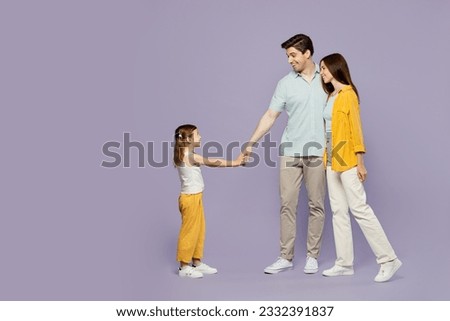 Full body fun young happy parents mom dad with child kid daughter girl 6 years old wear blue yellow casual clothes hold hand pov call follow me isolated on plain purple background. Family day concept