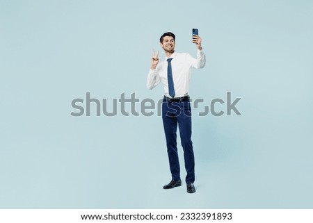 Full body young employee IT business man corporate lawyer wear classic formal shirt tie work in office doing selfie shot on mobile cell phone show v-sign isolated on plain pastel light blue background
