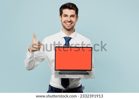 Young employee IT business man corporate lawyer wear classic formal shirt tie work in office hold use blank screen laptop pc computer show thumb up isolated on plain blue background studio portrait