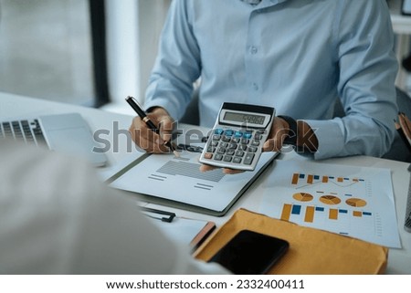 home loan officer uses a calculator with a house plan. Royalty-Free Stock Photo #2332400411