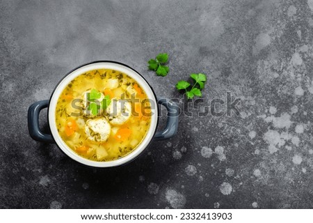 Chicken meatball soup in pot on dark background. Top view, copy space, flat lay. Royalty-Free Stock Photo #2332413903