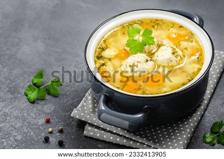 Homemade chicken vegetable meatball soup in pot on dark background. Top view, copy space, flat lay. Royalty-Free Stock Photo #2332413905