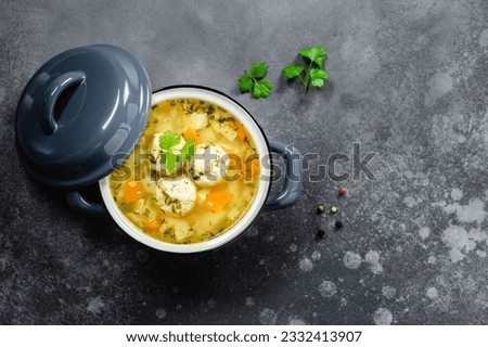 Healthy vegetable noodle meatball soup in pot on dark background. Top view, copy space, flat lay. Royalty-Free Stock Photo #2332413907