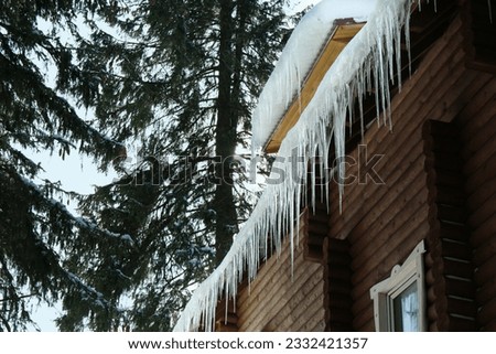 House with icicles on roof, low angle view. Winter season Royalty-Free Stock Photo #2332421357