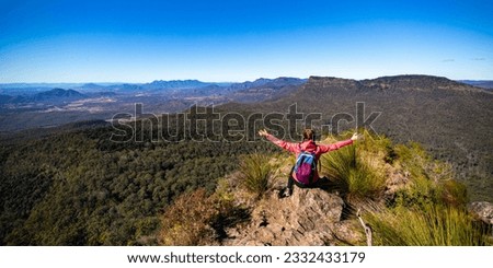 panoramic picture of backpacker girl enjoying the view from the top of Mount Mitchell after a successful hike, Main Range National Park, Gold, Coast, Queensland, Australia	