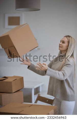 Caucasian girl taping boxes for moving in new apartment