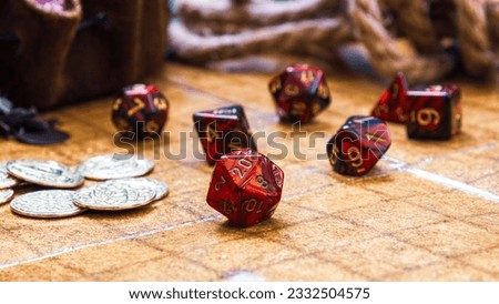 low angle shot featuring a collection of vibrant red RPG dice and golden gaming coins arranged on a battle map Royalty-Free Stock Photo #2332504575