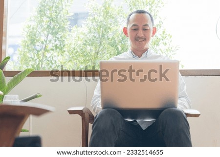 Young business man using laptop sitting at the chair in a home , l communicating online, writing emails, distantly working or studying on computer at home.