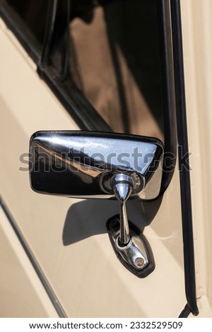 Chrome rearview mirror on beige retro car. Close-up.