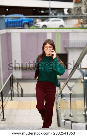 beautiful young caucasian businesswoman going up the stairs of the subway and talking on the cell phone Royalty-Free Stock Photo #2332541863