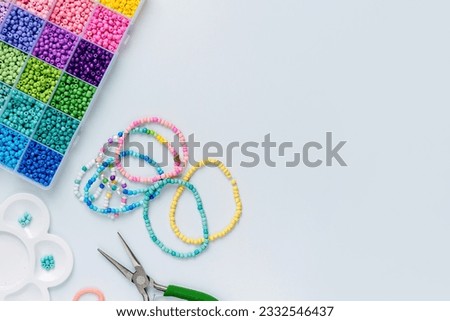 Set of for needlework and beading. Kids handmade beaded jewelry and different multi-colored beads for children's crafts in boxes. DIY art activity for kids. Motor skills, creativity and  hobby. Royalty-Free Stock Photo #2332546437