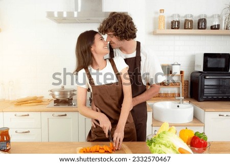 Romantic Happy couple preparing food having fun together Man girl standing in kitchen at home on first dating Spouses enjoy warm conversation and cooking process Care for health They are kissing Royalty-Free Stock Photo #2332570467